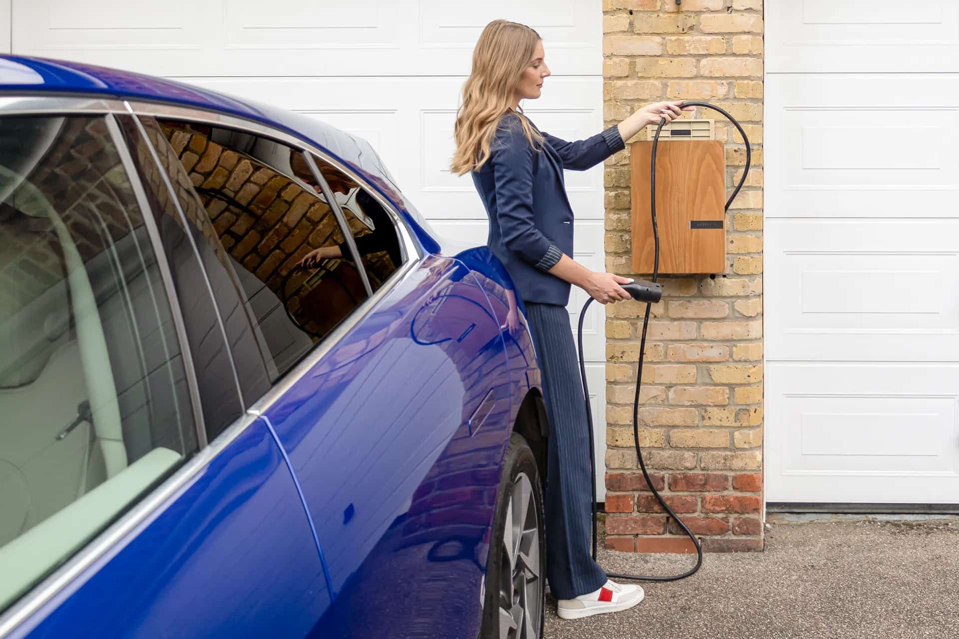 Žena nabíja svoj elektromobil doma, v pokojnej chvíli
